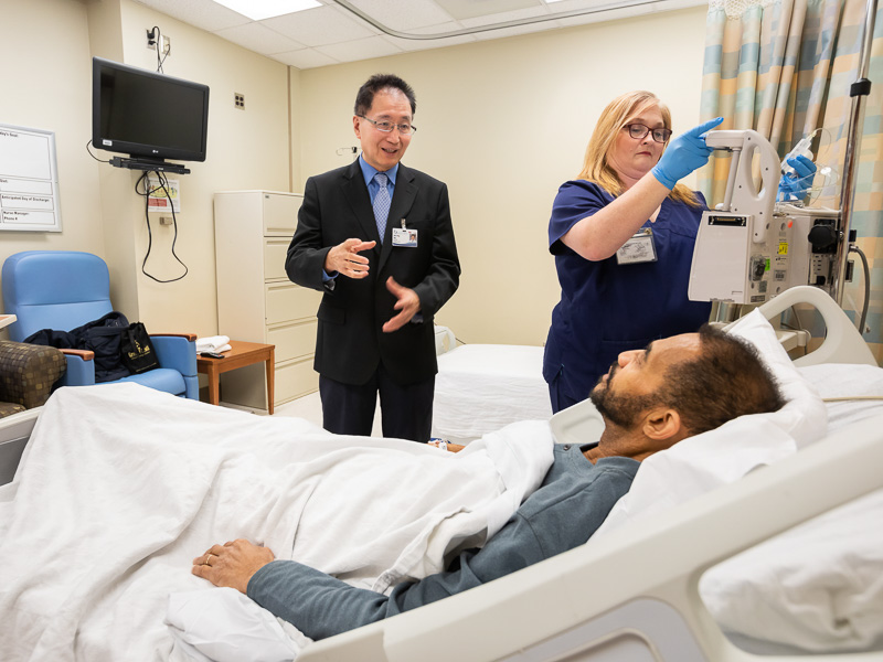 Dr. Shou-Ching Tang talks to Barry Kelly while Teresa Witcher, clinical trials nurse, prepares Kelly's infusion.